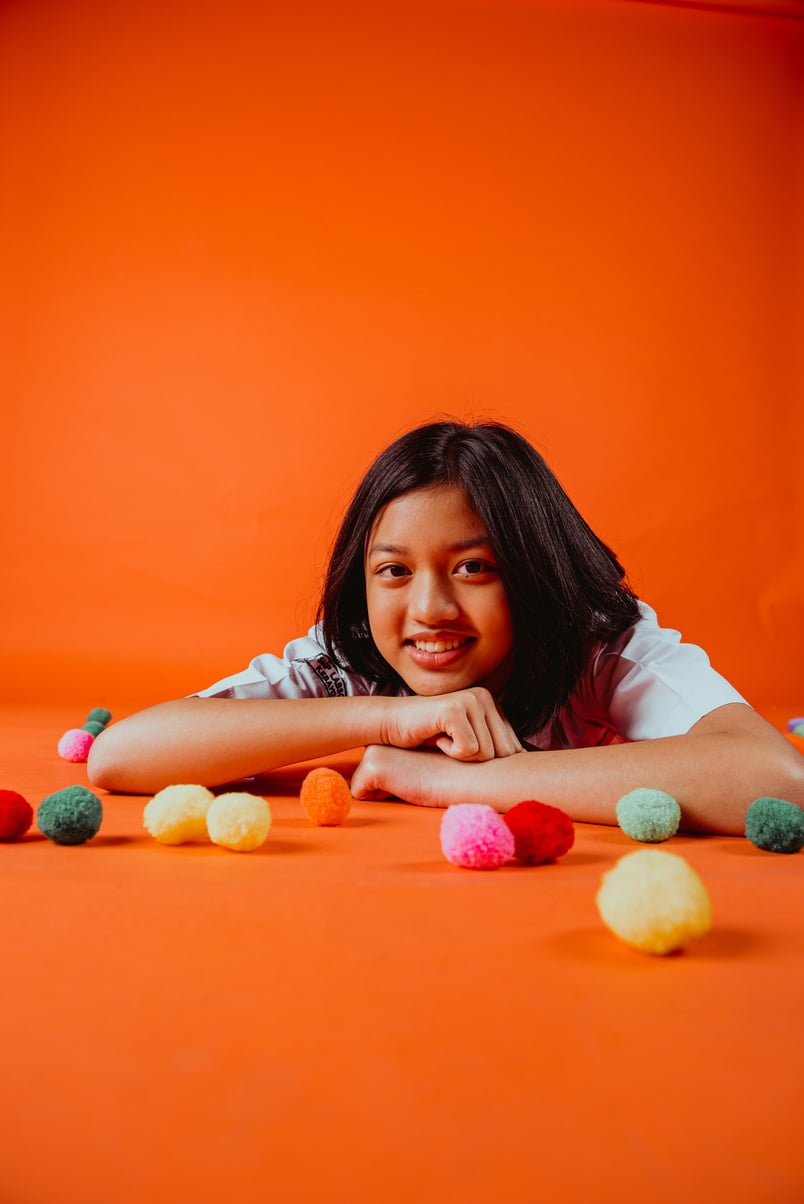 Smiling Teen Schoolgirl on the Floor with Colorful Balls