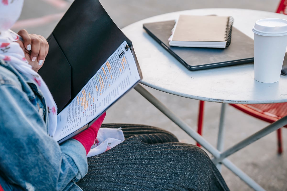 Student sitting at table and reading report in folder in daytime